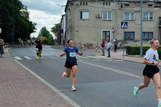 Pojedynczy zawodnicy biegnący na tle zabudowy miejskiej