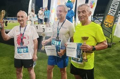 Zdjęcie przedstawia biegaczy stojących medalami na szyi i z pucharami