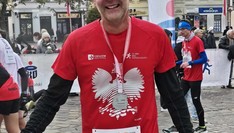 Biegacz w czerwonej koszulce z orłem i medalem