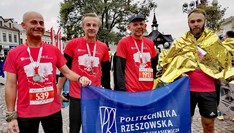 Zdjęcie przedstawia zawodników Klubu Biegacza PRz z flkagą PRz