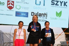 Panie stojące na podium dla zwycięzców na tle banera
